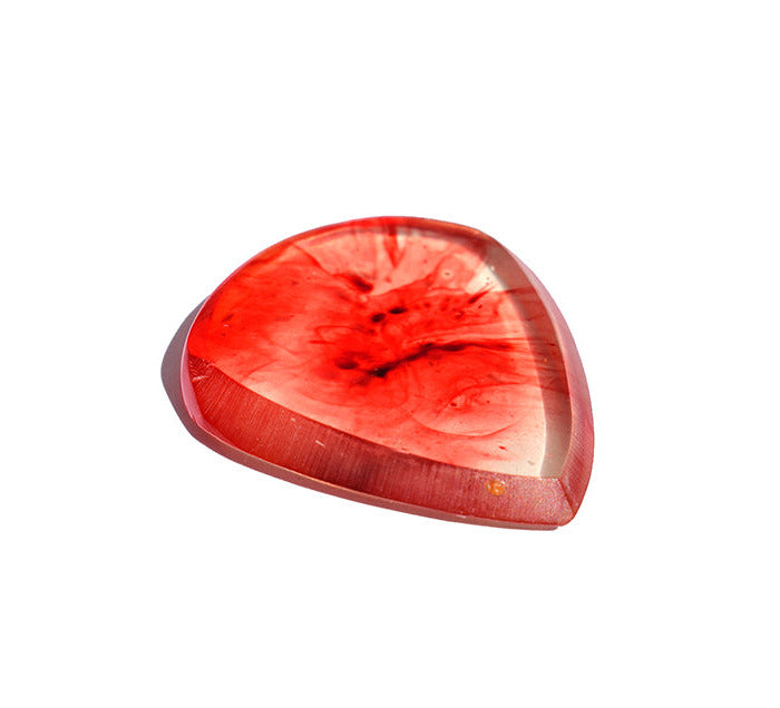 A polished,  red resin guitar pick with swirling patterns that look like blood