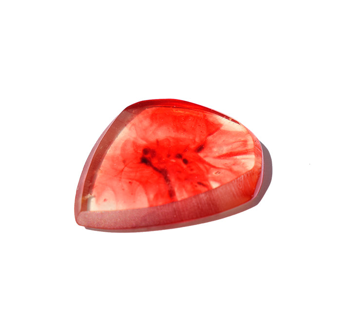 Right side view of a polished red resin guitar pick that looks like blood in water