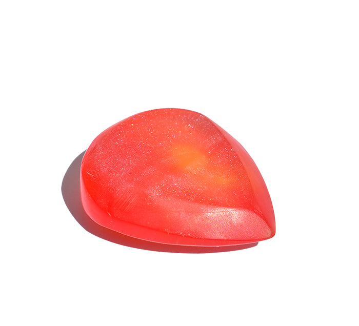 The left side view of a  translucent red teardrop-shaped resin guitar pick with fine glitter