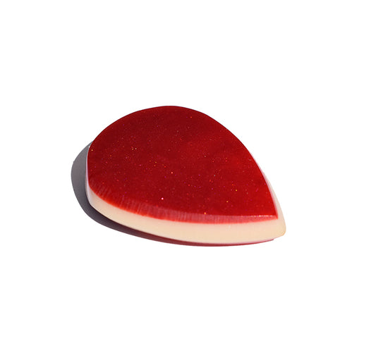 Left side angle of red glitter resin guitar pick showing light bevel edge profile