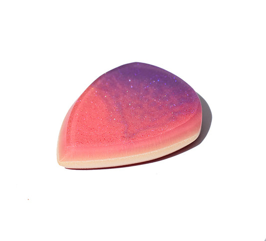 Right side angle of pink and purple glitter swirl resin guitar pick showing bevel profile